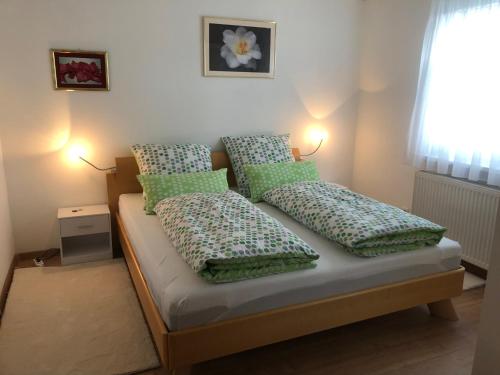 a bed with green pillows on it in a room at Ferienwohnung in ruhigem Viertel in Rhodt unter Rietburg