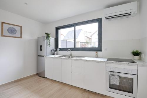 une cuisine blanche avec un évier et une fenêtre dans l'établissement Maison Créteil - Maison climatisée avec jardin, à Créteil