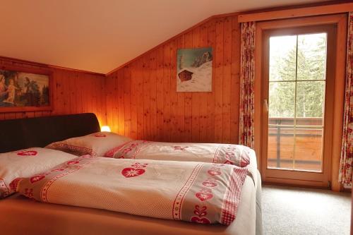 1 dormitorio con 2 camas y ventana en Almchalet Goldbergleiten, en Großkirchheim