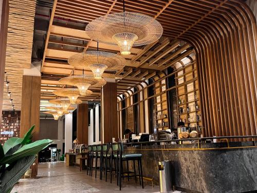 a restaurant with a bar with chairs and chandeliers at Luminor Hotel Legian Seminyak - Bali in Legian