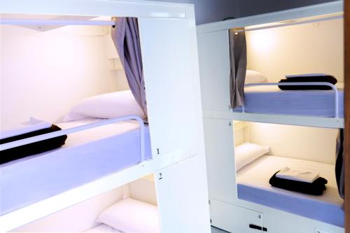 a locker room with white bunk beds at Black Swan Hostel Granada in Granada