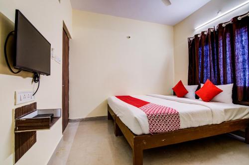 a bedroom with a bed with red pillows and a tv at Flagship URBAN DRIFT in Yelahanka