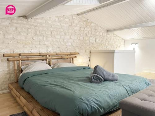 ein großes Bett in einem Schlafzimmer mit einer Steinmauer in der Unterkunft Le Paul by iZiLi - Centre Ville - Gare in Niort