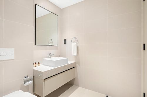 a white bathroom with a sink and a mirror at Silkhaus Beach Vibes in Tower with Private Beach in Dubai