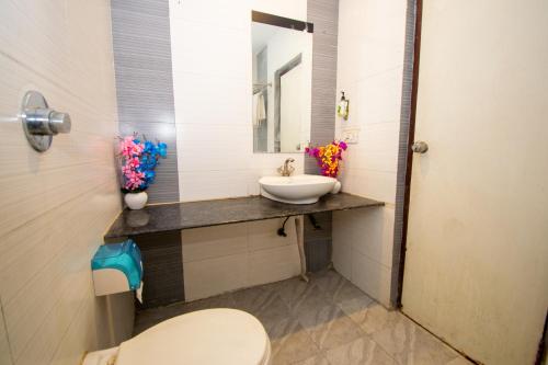 a bathroom with a sink and a toilet and a mirror at Octave Verdisso Hotel in Bangalore