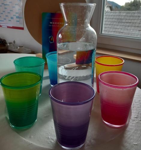 four colorful cups sitting on a counter with a vase at Kunterbunt Seehaus in Faak am See