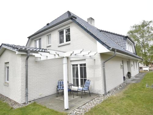 una casa bianca con un tavolo e sedie su un portico di Calm Holiday Home with Garden in Zingst Germany a Zingst