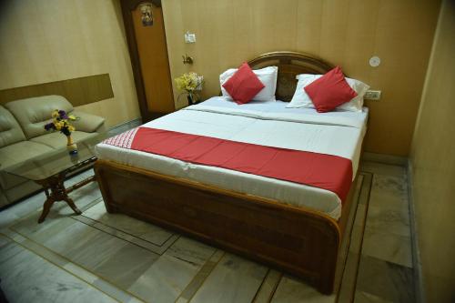 1 dormitorio con cama con almohadas rojas y sofá en Collection O City Heart, en Hisār