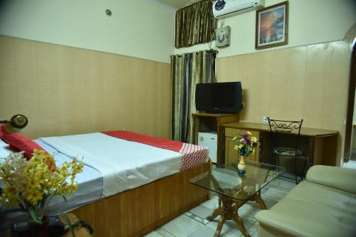 a bedroom with a bed and a table and a tv at Collection O City Heart in Hisār