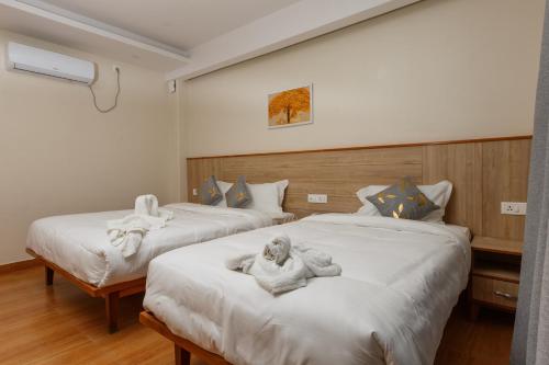 two beds in a room with dolls on them at Samiyog Tourist Resort in Pokhara
