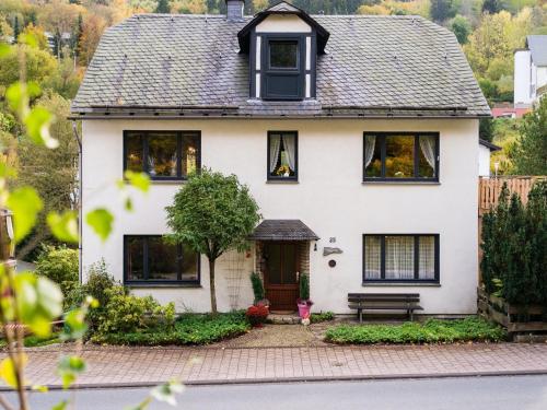 a white house with a bench in front of it at Large detached holiday home in Willingen with garden in Willingen