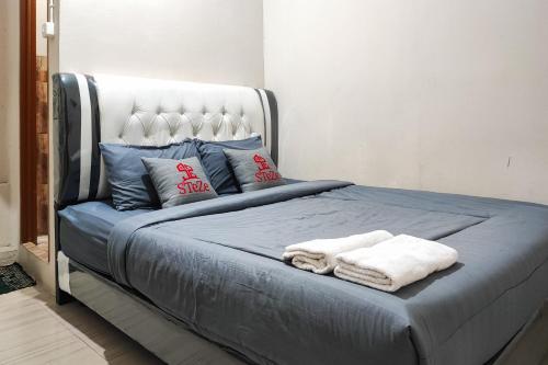 1 cama con 2 toallas en un dormitorio en Urbanview Hotel Syariah near Jamtos, en Jambi