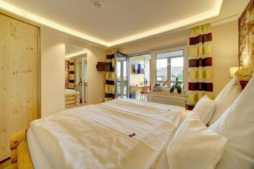 a large white bed in a room with a window at Hotel Hirschenstein in Achslach