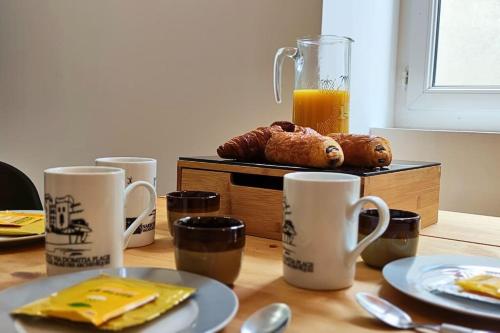 une table avec des tasses, des assiettes et un pichet de jus d'orange dans l'établissement El Dino in country cathare*PRO*Oc Keys011, à Espéraza