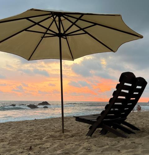a beach chair and an umbrella on the beach at CAFE MAYA in Zipolite