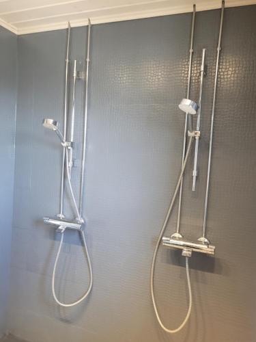 a bathroom with two shower heads on a wall at Villa Onnela Ämttöö in Pori