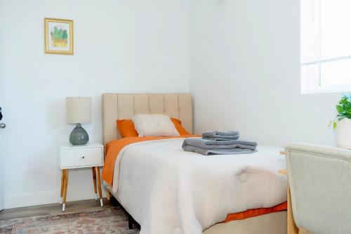 a bedroom with a white bed with an orange blanket at THE SECRET GARDEN in Los Angeles