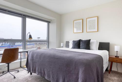 um quarto branco com uma cama, uma secretária e uma janela em Blueground E Cambridge gym wd near T stop BOS-967 em Boston