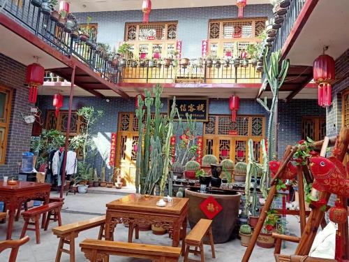 a patio with tables and potted plants in a building at Pingyao Jiaxin Guesthouse in Pingyao