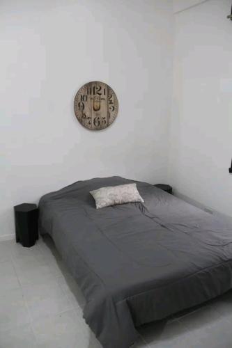 uma cama num quarto branco com um relógio na parede em Martínez em Guaymallén