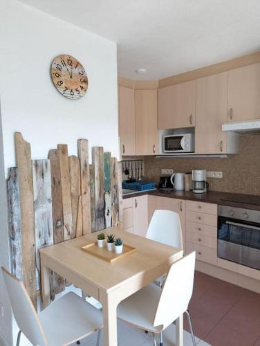 - une cuisine avec une table en bois et des chaises blanches dans l'établissement Appartement à Seignosse Le Penon - 200m plage, à Seignosse