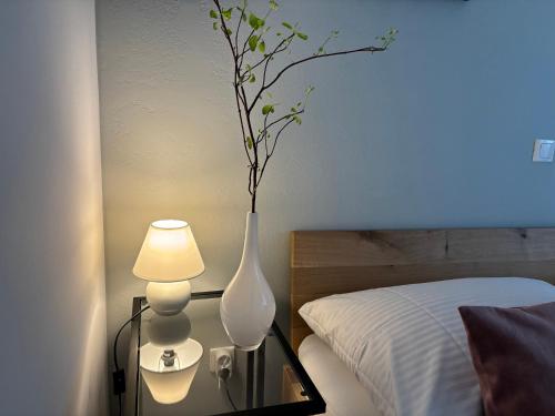 a white vase sitting on a glass table next to a bed at Ljubljanica Apartment in Ljubljana