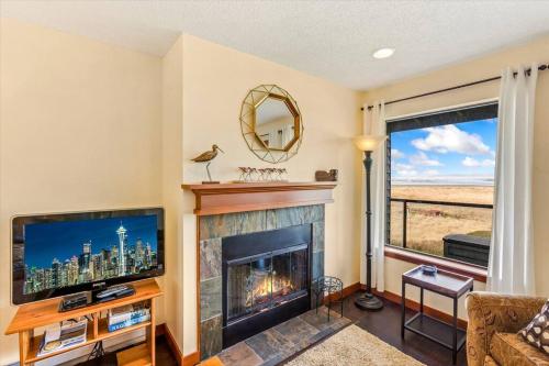 a living room with a fireplace and a television at Whale Song Condo #29 in Moclips