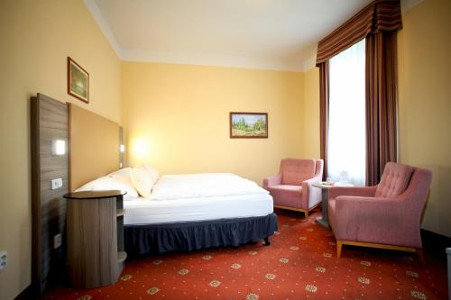 een hotelkamer met een bed en twee stoelen bij Hotel Paris in Mariánské Lázně