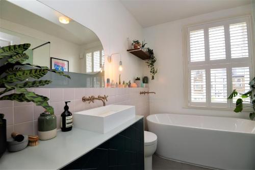 La salle de bains est pourvue d'une baignoire blanche et d'un lavabo. dans l'établissement 2 Bed House with garden - 20mins to London Stadium, à Londres