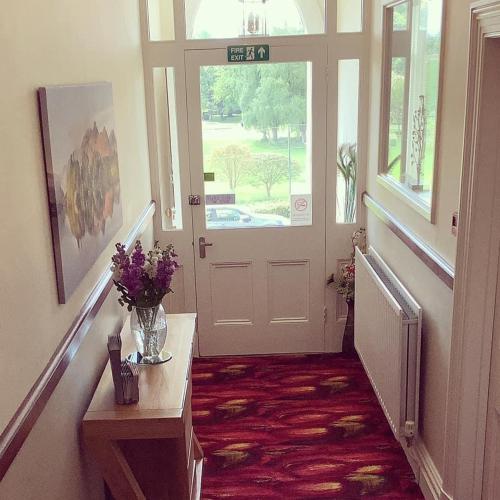 a hallway with a door with a vase of flowers at Burleigh Mead in Keswick