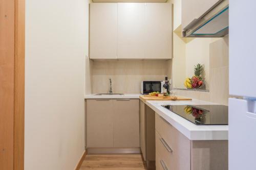 uma pequena cozinha com armários brancos e um lavatório em Host Wise - Porto Urban Escape no Porto
