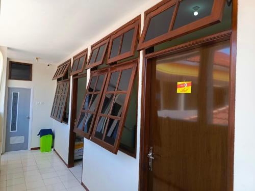 a hallway with a wooden door and glass cabinets at Bebek Kuning Residence in Blimbing