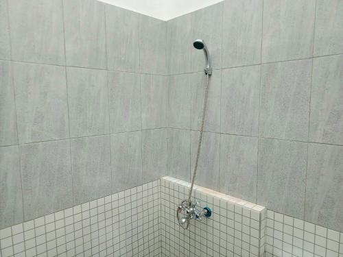 y baño con ducha y pared de azulejos. en Bebek Kuning Residence, en Blimbing