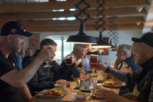 Eine Gruppe Männer, die an einem Tisch sitzen und Wein trinken. in der Unterkunft Halmstad Tönnersjö Golfbana in Eldsberga