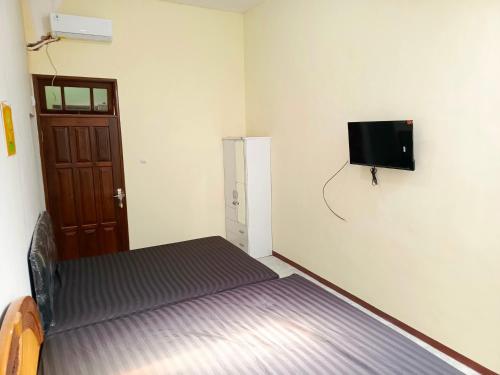 a room with a bed and a tv on the wall at Bebek Kuning Residence in Blimbing