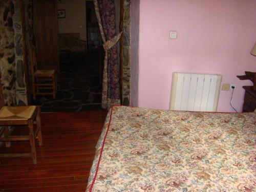 a bedroom with a bed with a flowered blanket on it at Casa Rural La Ortiga in Robledillo de Gata