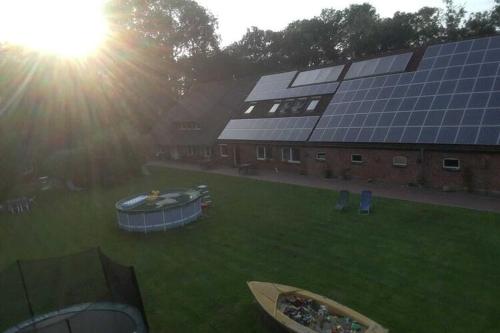 een groot gebouw met zonnepanelen op het gras bij Ferienhof Landhaus Markus Southern Switzerland in Süderschwei