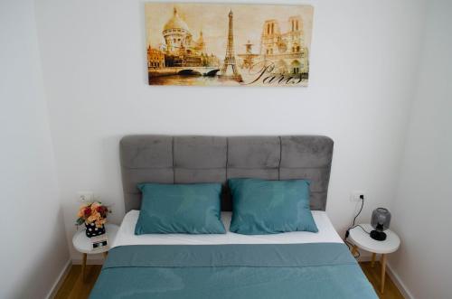 a bed with blue pillows and a painting on the wall at Kuća za odmor 'Luca' in Ljubuški