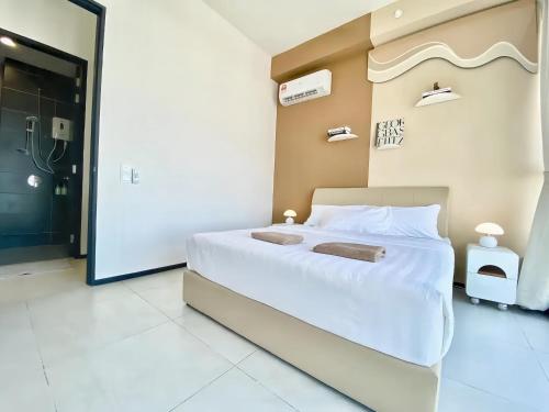 a bedroom with a large white bed with two towels on it at Urban Suites George Town in Jelutong