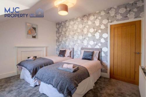 a bedroom with two beds and a wall with flowers at The Old Bank in Hawick