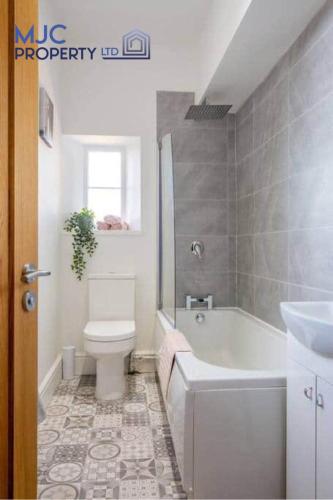 a bathroom with a toilet and a tub and a sink at The Old Bank in Hawick