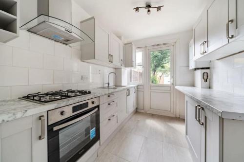cocina con armarios blancos y fogones en A Luxurious 3 Bed-Terrance House en Londres