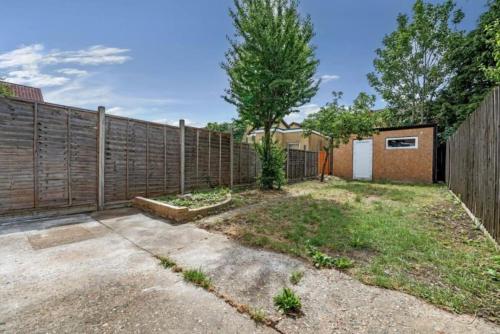 a backyard with a wooden fence and a driveway at A Luxurious 3 Bed-Terrance House in London