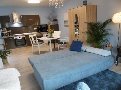 a living room with a blue couch and a kitchen at Apart Charmant Köthen in Köthen