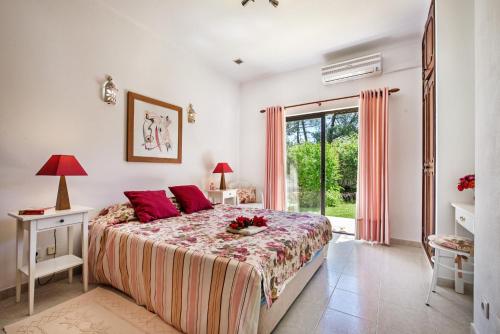 um quarto com uma cama com almofadas vermelhas e uma janela em Barros em Albufeira