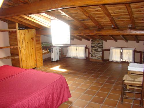 a large room with a bed and a stone wall at Casa Rural La Ortiga in Robledillo de Gata