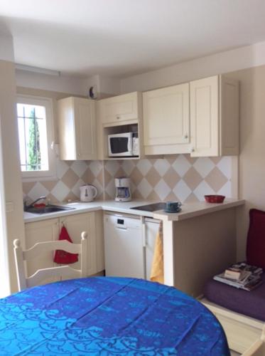 une petite cuisine avec des placards blancs et une table bleue dans l'établissement joli 2 pieces vue mer , piscine proche ste Maxime résidence BELLEVUE, à Roquebrune-sur Argens