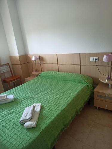 a bedroom with a green bed with towels on it at Jardines del Mar in Oropesa del Mar