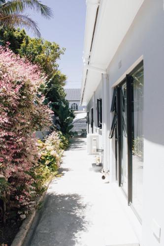 a sidewalk next to a white building with pink flowers at Tranquil Private Rooms Hermanus in Hermanus