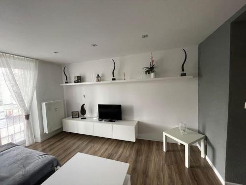 Habitación blanca con cama, TV y mesa. en Gray&Wood, en Prievidza